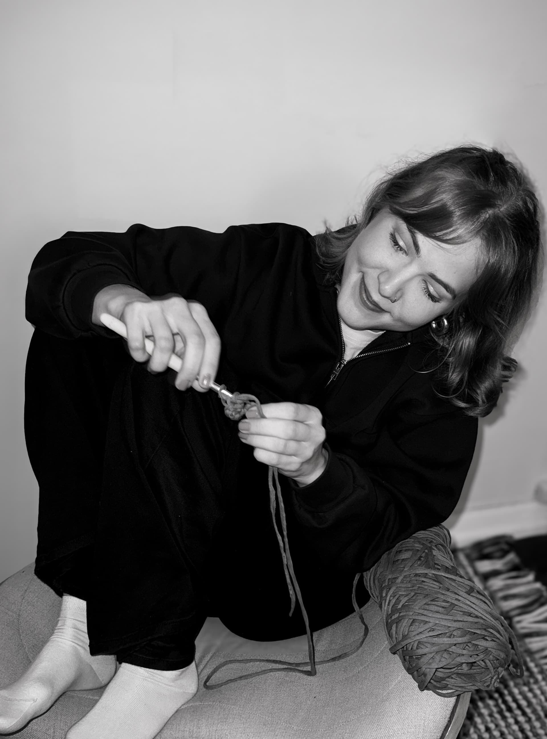 One of the sisters crocheting by hand, a ball of yarn beside her.